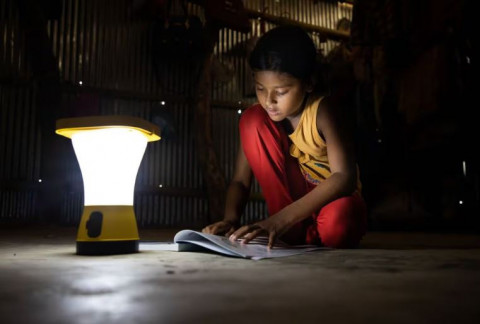 Una niña lee en su casa utilizando una luz de energía solar en Jaliyapalong, Cox's Bazar, Bangladés.